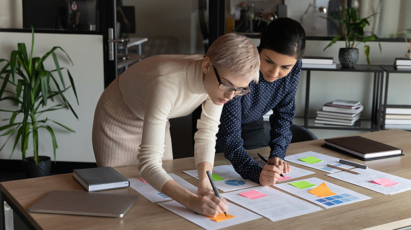 ACA compliance report review Decorative photo showing two female coworkers reviewing reports in a conference room